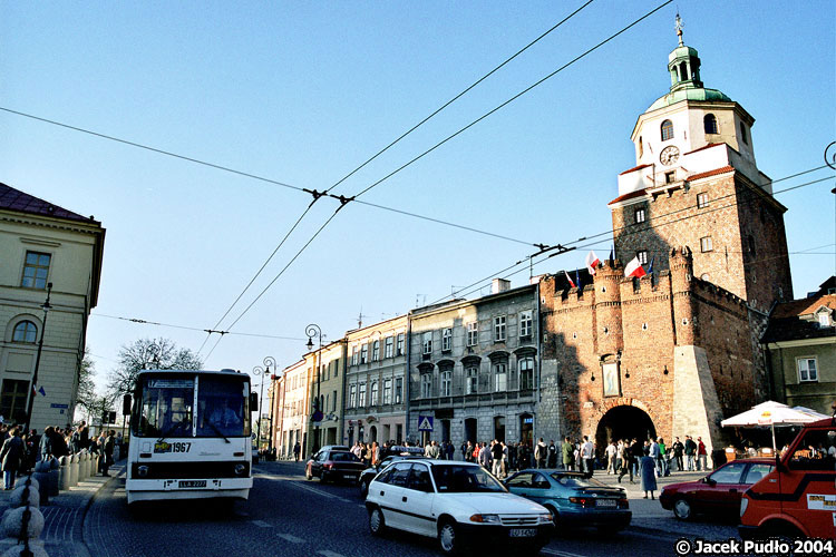 1967
Zagadnienie sfotografowania pojazdu komunikacji z Bramą Krakowską intrygowało mnie od dawna. Zadanie jest trudne, gdyż układ budynków skutecznie utrudnia ujęcie bramy. Stąd też pierwsze podejście do tematu nie było zachwycające.
