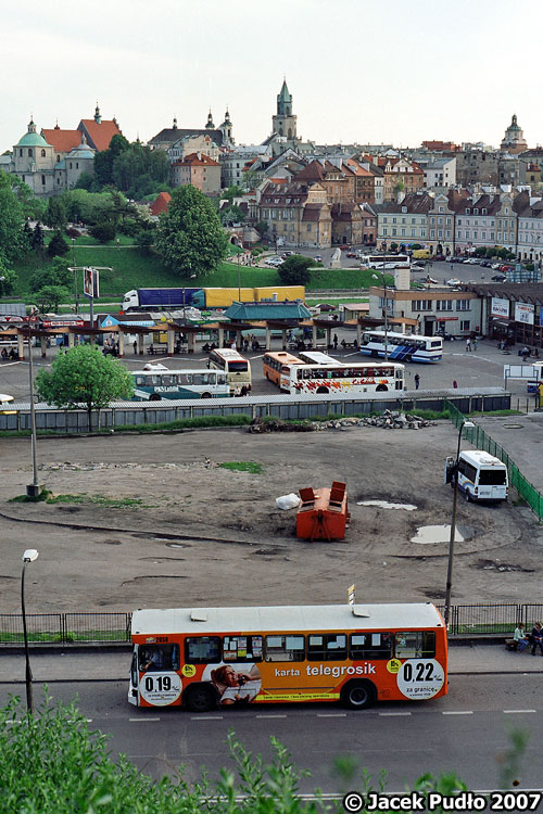 2058
Jelcz na dwójce oczekuje na porę odjazdu. Nieco za nim obskurny plac postojowy dla autobusów, dalej Dworzec PKS, na kolejnym planie ciężarówki na al. 1000-lecia, a za nimi wzgórze zamkowe, Plac Zamkowy i lubelska starówka. Na linii horyzontu widoczne od lewej: Kościół Dominikanów, Katedra, Wieża Trynitarska, a w prawej części kadru Brama Krakowska.
Słowa kluczowe: lubelska_starowka