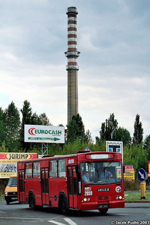 2059
Na pierwszym planie jelcz M11 rocznik 1988, a do towarzystwa komin fabryki samochodów o burzliwej historii - pierwotnie FSC, później Daewoo Lublin, po upadłości - własność Intrallu, który obecnie również jest w upadłości. Niestety, zapewne przepadnie przez to projekt kolejnego następcy dostawczego Lublina - Lubo. Poprzednim był LD-100, dla którego powstała nawet hala. Jednakże upadłość Daewoo uniemożliwiła rozpoczęcie produkcji, a projekt samochodu przejęła brytyjska firma motoryzacyjna.
