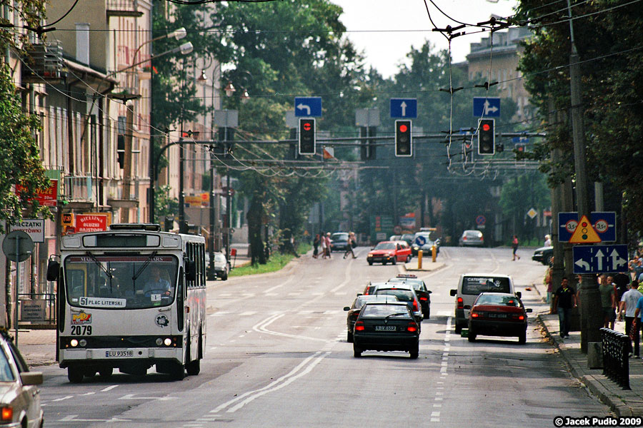 2079
Ulica Lipowa. A gdzie lipy? Połowa zniknęła, gdy budowano Plazę, a niedobitki zostały po lewej stronie i w dalszej części ulicy. Zmieniając temat na sieć trakcyjną - przy względnie wysokiej temperaturze i dużej ogniskowej łatwo dostrzec wydłużanie się miedzianych przewodów. Obecnie stosuje się przewody jezdne Djp100 o powierzchni przekroju 100 mm2, wykonane z twardej miedzi.
