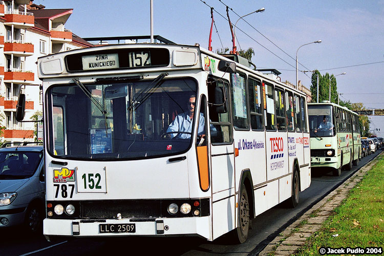 787
Trolejbus delikatnie stuningowany - zaklejono dolne części narożnych szyb, na gumowych kłach zderzaka są odblaski, a do obserwacji przestrzeni pasażerskiej służy się zdaje oryginalne lustro z Ikarusa. Co typowe dla trolejbusu PR110E/T, nad lewym lusterkiem jest dodatkowe małe lustro do obserwacji pałąków. Trolejbus jeszcze z klasycznymi kołami i oponami dętkowymi, a na ścianie czołowej rzadka tablica z zielonym kolorem czcionki.
